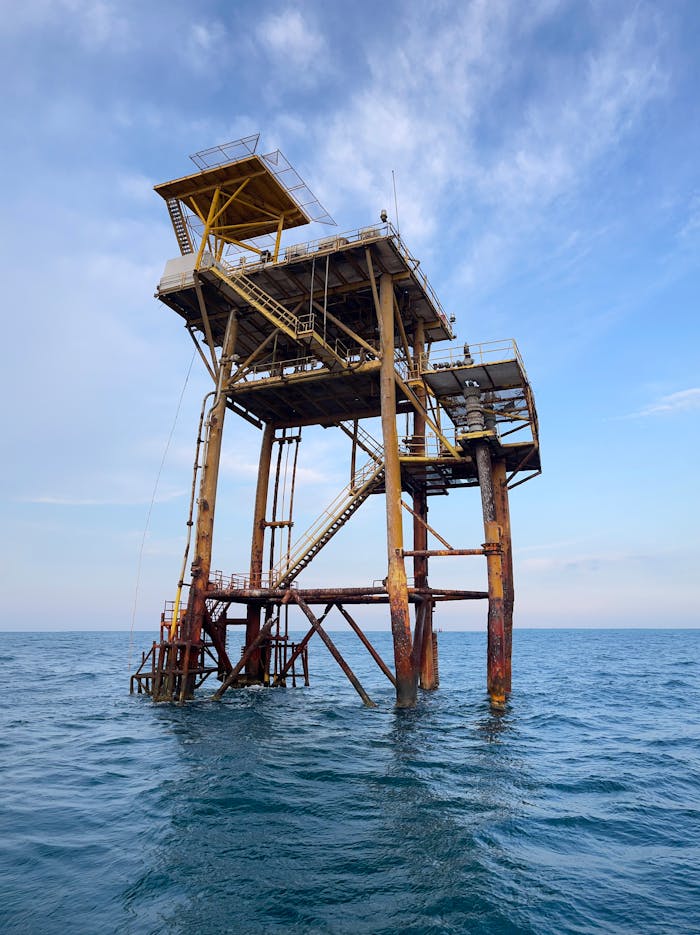 Tall offshore oil platform structure in the middle of the ocean against a clear blue sky.