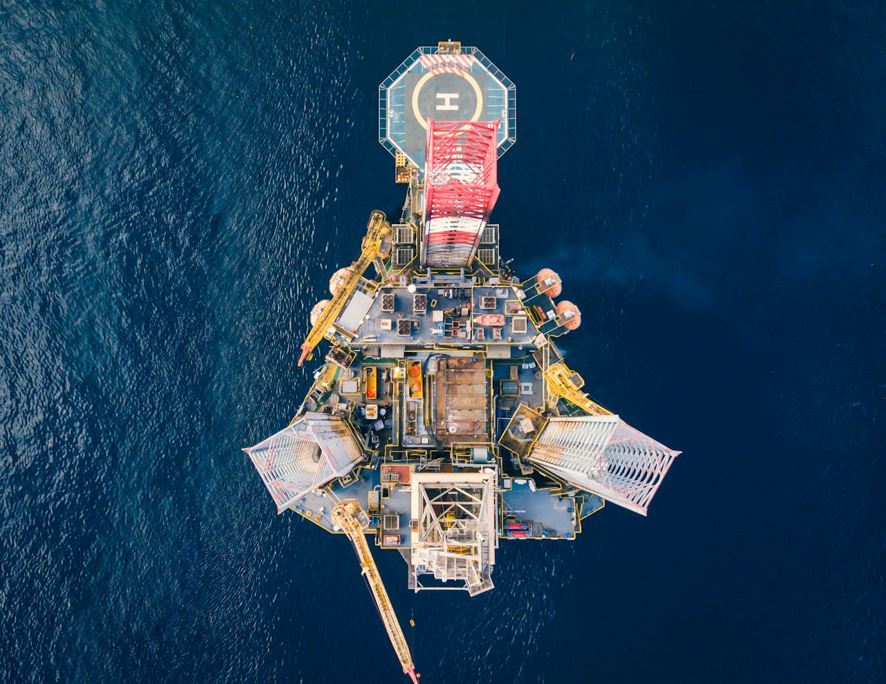 services-img High-angle view of an offshore oil platform with helipad surrounded by deep blue ocean.