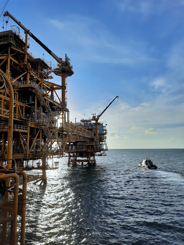 The Art of Drawing Readers In: Your attractive post title goes here A large offshore oil rig with a supply vessel in the open sea under a blue sky and sunlight.